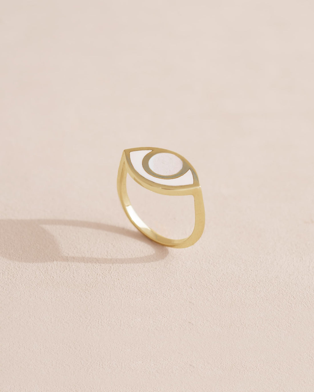 A porcelain ring with a gold band, designed to resemble an eye, placed on a light background.