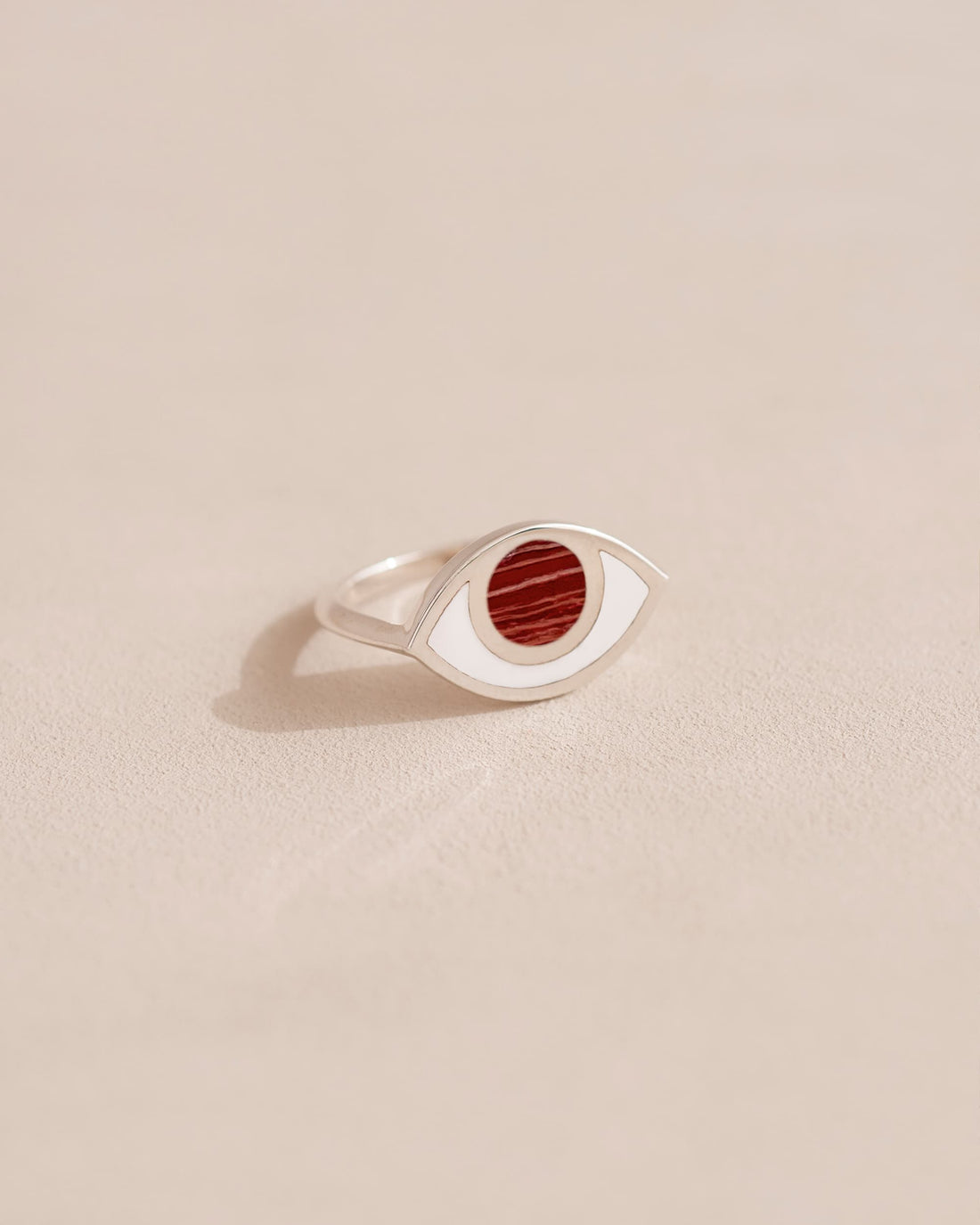 A silver ring with a snake skin jasper stone set in the center, placed on a light background.