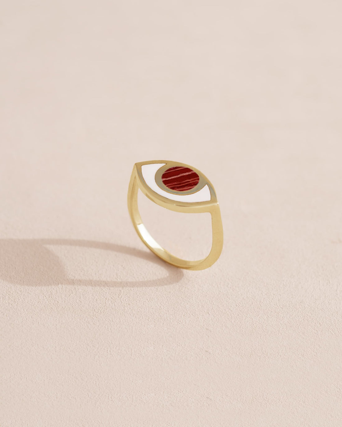 Gold ring with red stone on a light beige background