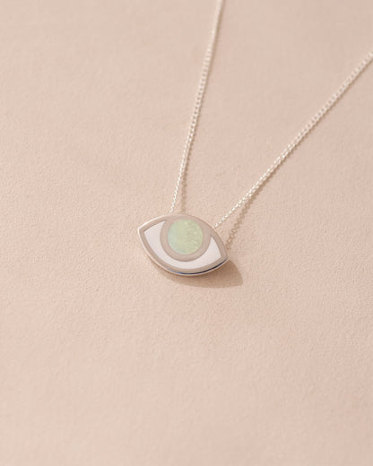 A silver pendant necklace with a round opal stone set in a eye-shaped frame, displayed against a light background.