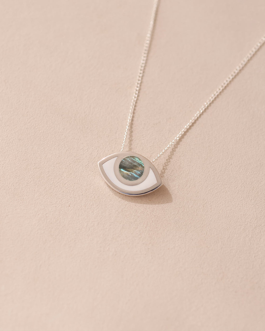 A silver pendant necklace with a labradorite stone in the shape of an eye, displayed against a light background.