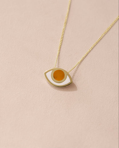 A 14K yellow gold pendant necklace with an eye design featuring an orange stone in the center, displayed against a light background.