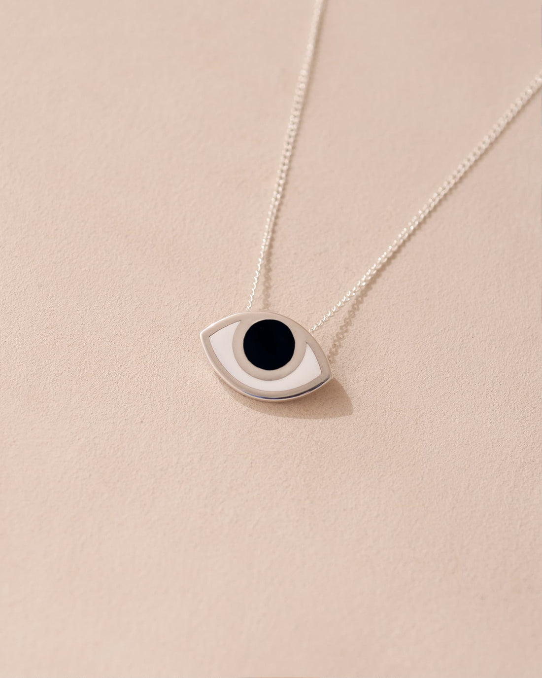 A silver pendant necklace with a onyx stone shaped like an eye, displayed against a light background.