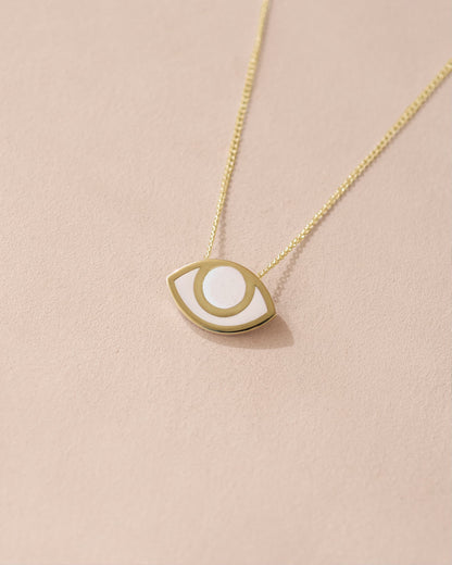 A porcelain pendant necklace with a gold eye design, displayed against a beige background.