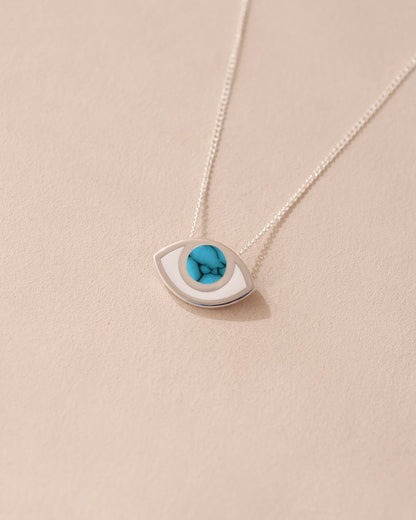 A silver pendant necklace with a turquoise eye-shaped talisman on a light background.