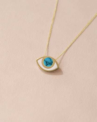 A 14K yellow gold pendant necklace with a turquoise eye design on a light background.