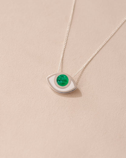 A silver pendant necklace with a variscite stone shaped like an eye, displayed against a beige background.