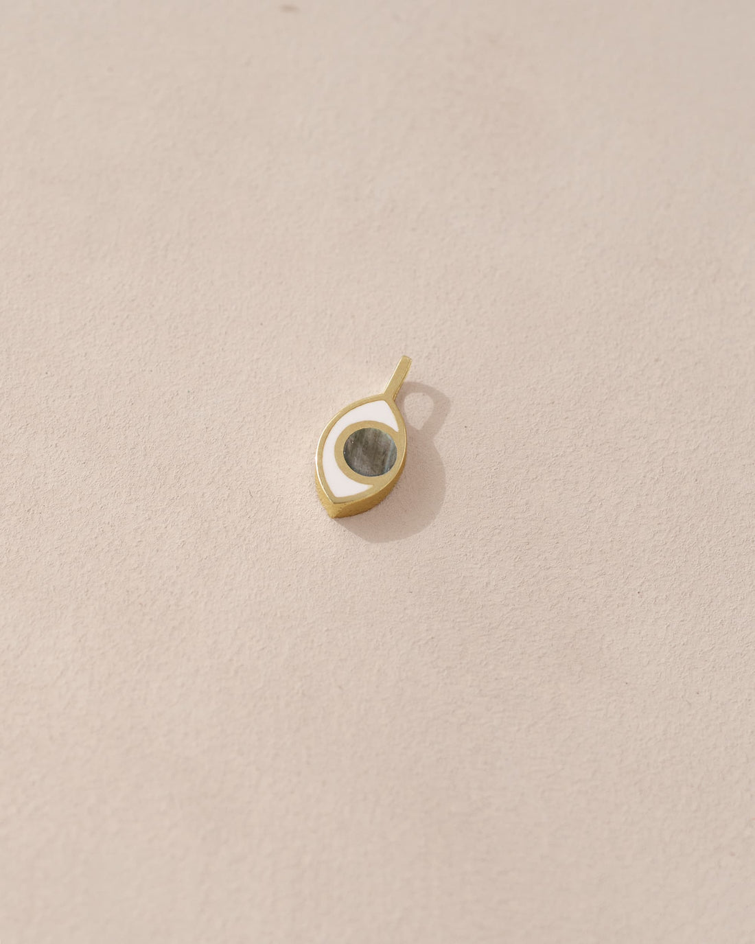 Small gold and black pendant on a beige background