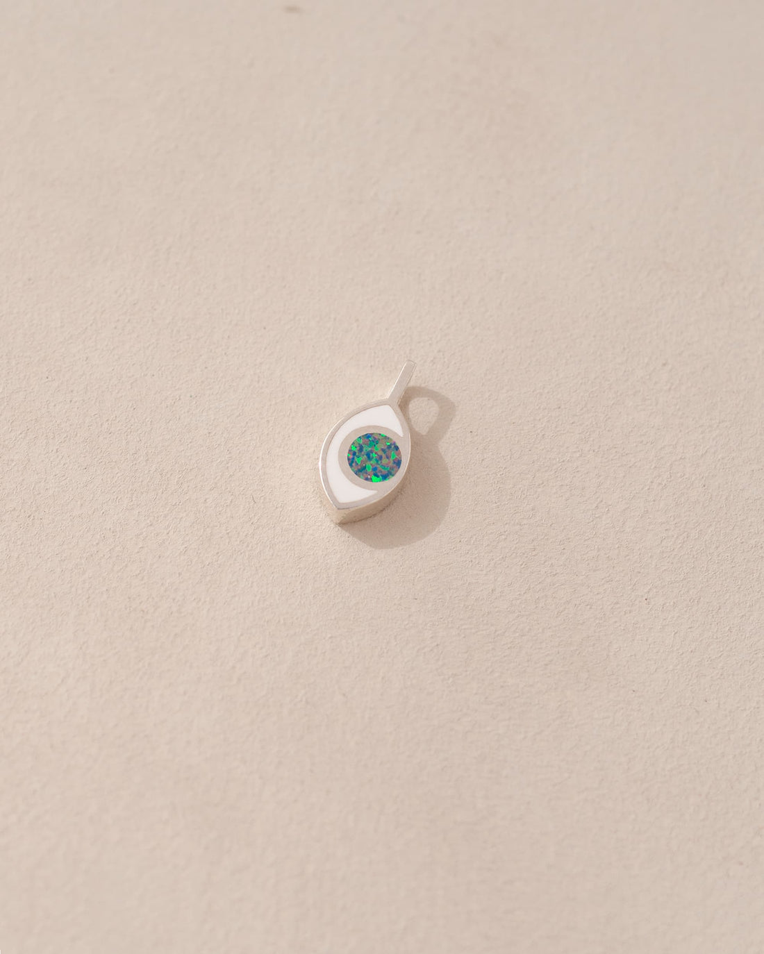 a silver charm shaped like an eye featuring a round opal stone