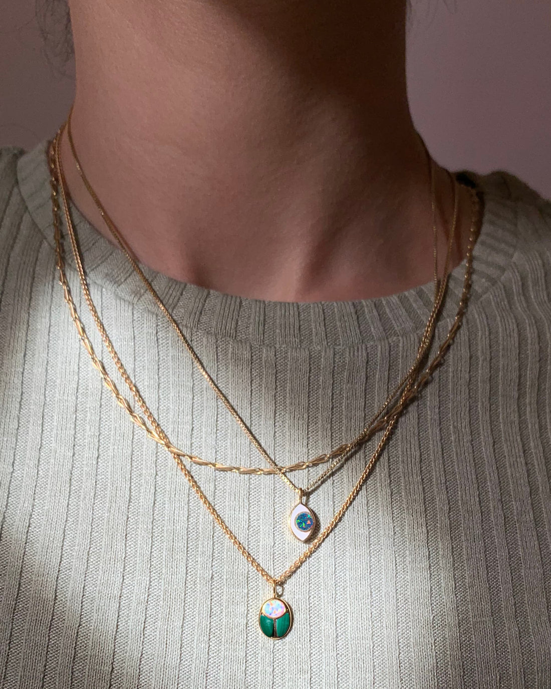 model wearing a scarab and an eye charm on gold chains