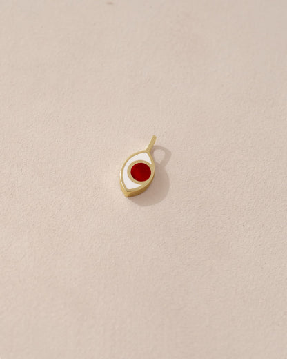A small 14K yellow gold charm with a carnelian stone shaped like an eye.