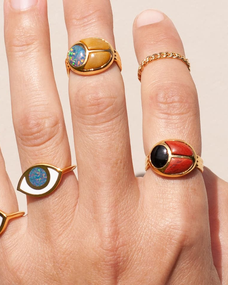 a close up of a hand wearing multiple gold rings inlayed with different stones