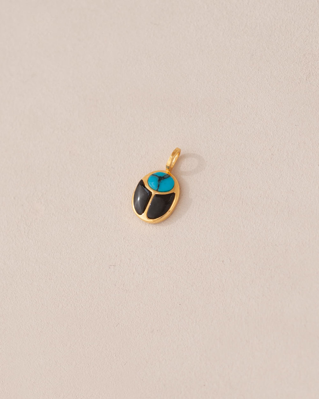 A 14K yellow gold charm in the shape of a scarab amulet with turquoise and onyx inlays, displayed against a neutral background.
