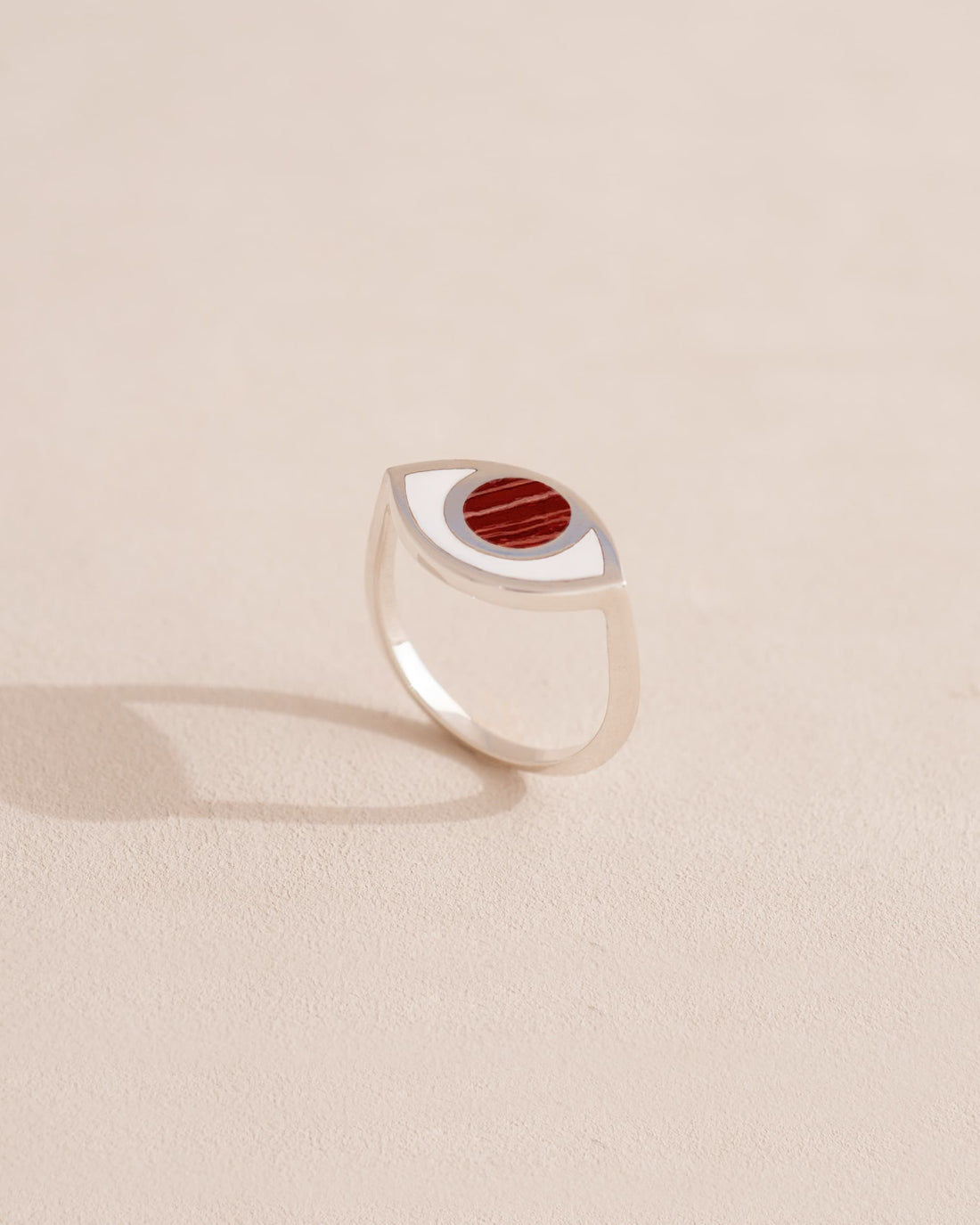 Silver ring with red stone on a light beige background